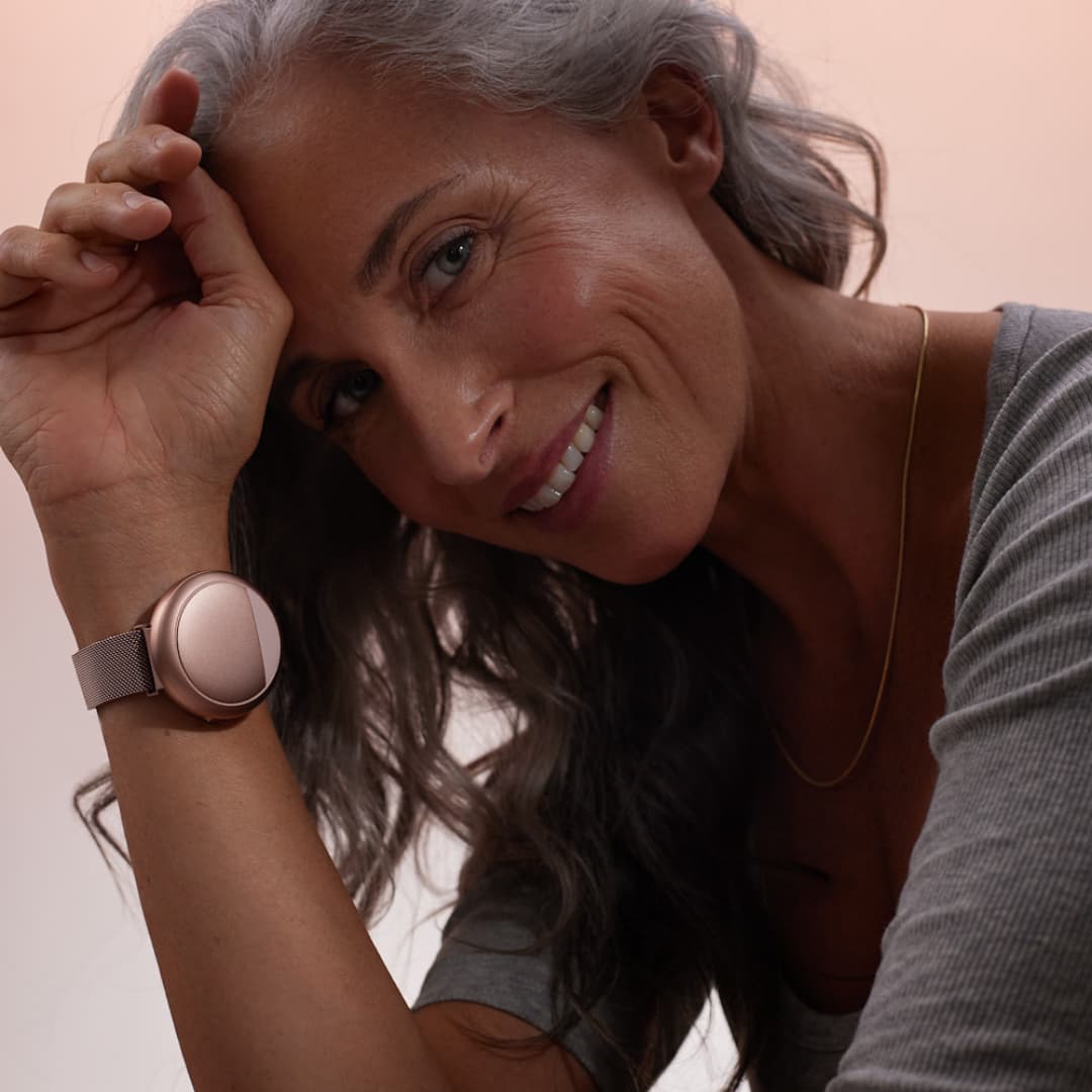 Smiling woman wearing Embr Wave 2 Cooling and Warming Smart Wristband Rose Gold - Embr Labs