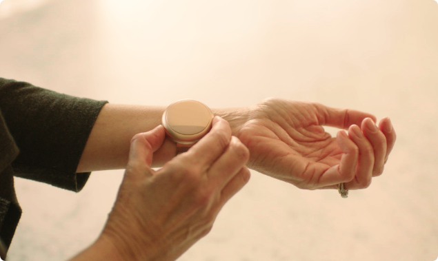 Woman adjusting the rose gold Embr Wave 2 on her left wrist.