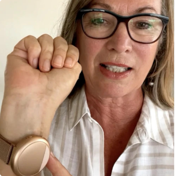 Woman with glasses models the rose gold Embr Wave 2 on her right wrist.