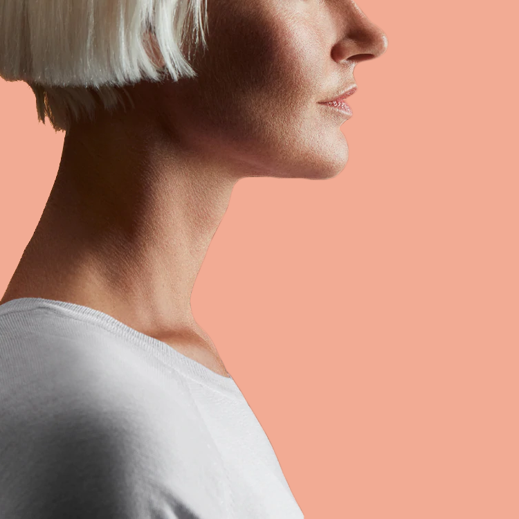 Profile of woman's upper body against peach background.