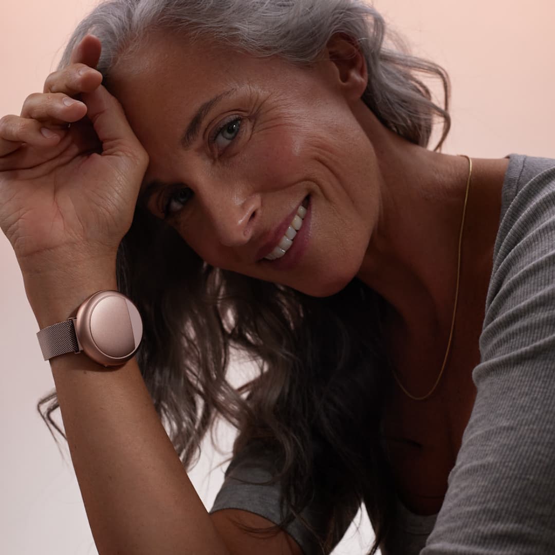 Smiling woman wearing Embr Wave 2 Cooling and Warming Smart Wristband Rose Gold  - Embr Labs